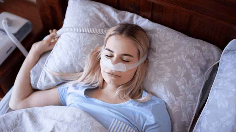 A young woman peacefully sleeping in bed with a CPAP machine for sleep apnea.