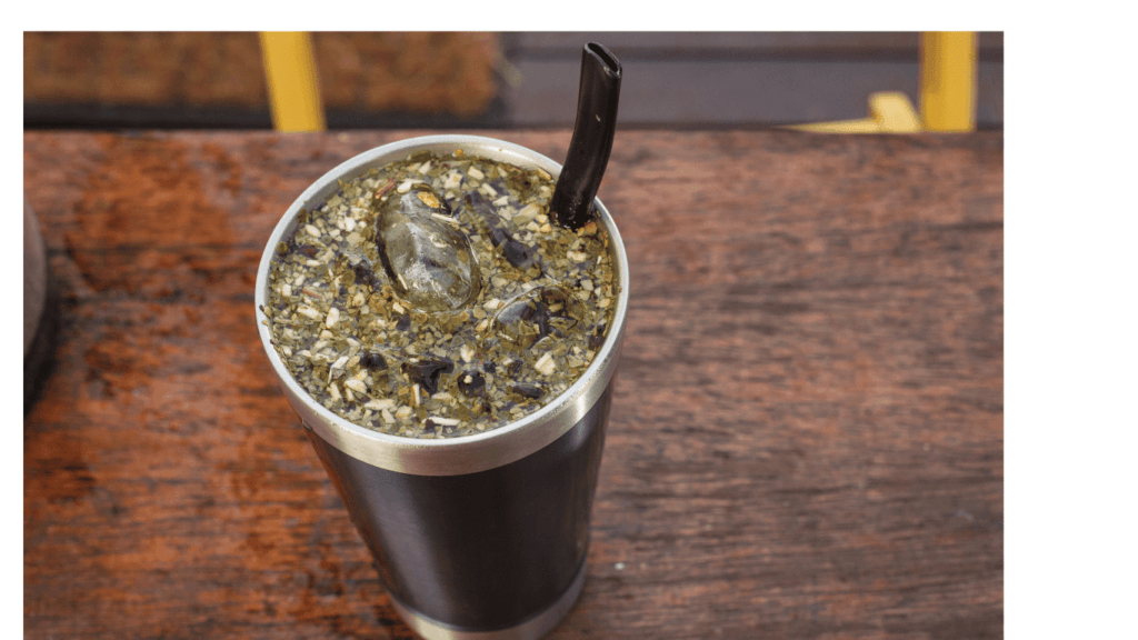 A glass of tereré, cold herbal tea from Paraguay, with ice, mint leaves, and a metal straw.