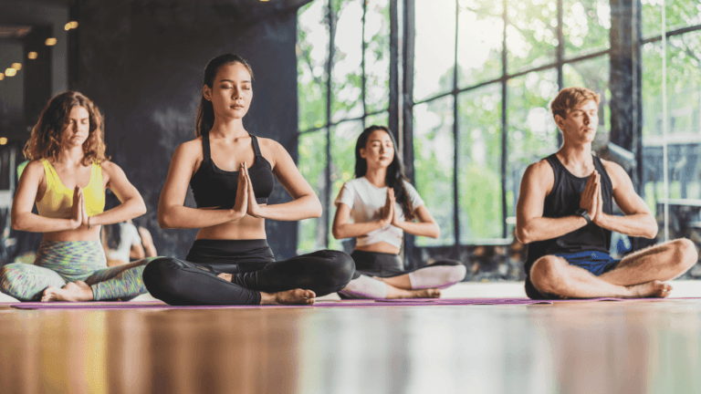 A diverse group of men and women practicing somatic yoga through breath awareness and body sensations.